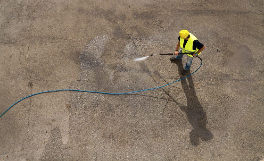 一个男人用强力清洗机清洗工业地板
